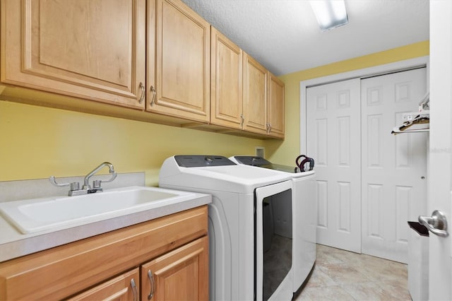 laundry area featuring separate washer and dryer, sink, cabinets, and a textured ceiling