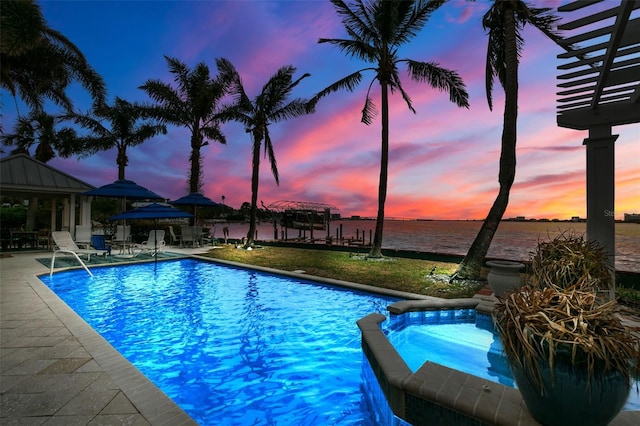 pool at dusk with an in ground hot tub, a gazebo, a water view, and a patio area