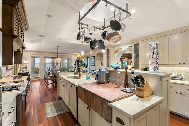 kitchen featuring cream cabinetry, dark hardwood / wood-style floors, pendant lighting, and an island with sink