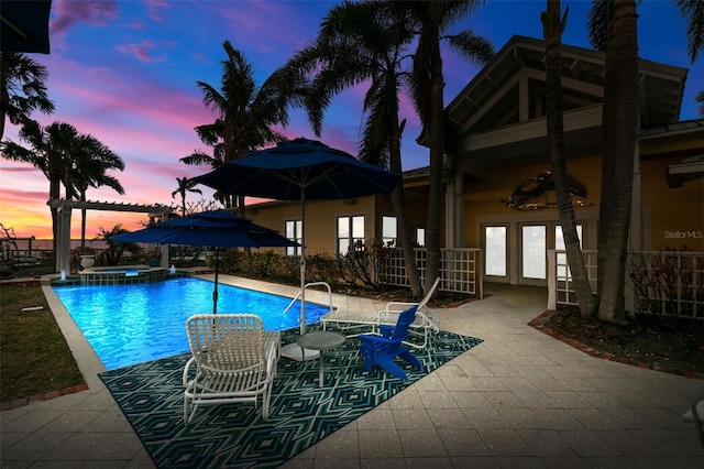 pool at dusk with a patio area and an in ground hot tub