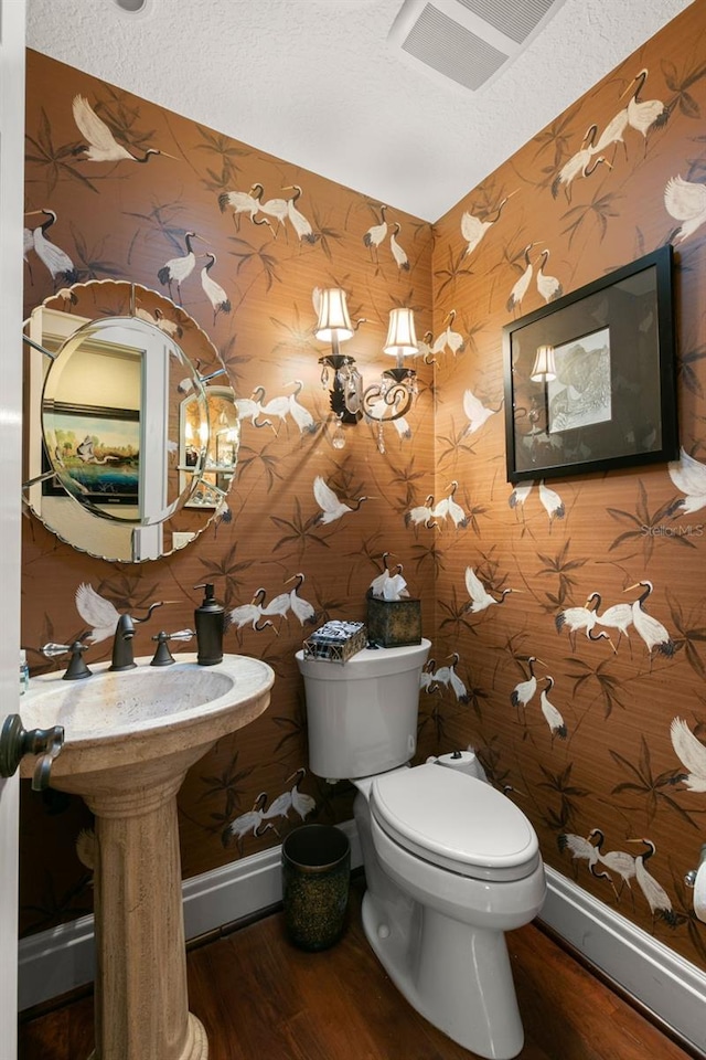 bathroom with hardwood / wood-style floors, a textured ceiling, and toilet