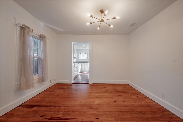 empty room featuring hardwood / wood-style floors and a chandelier