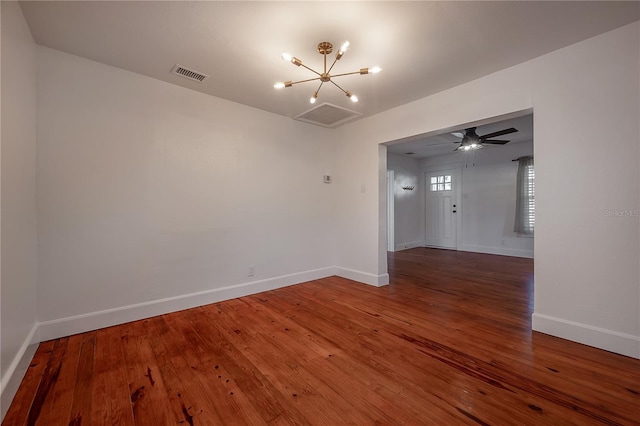 spare room featuring wood-type flooring and ceiling fan with notable chandelier