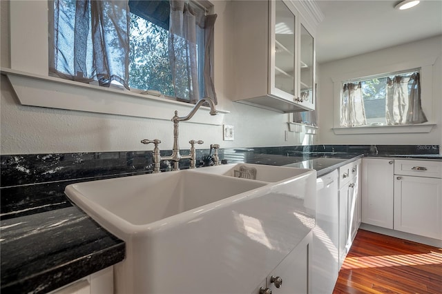 kitchen with white cabinetry, hardwood / wood-style flooring, sink, and dark stone countertops