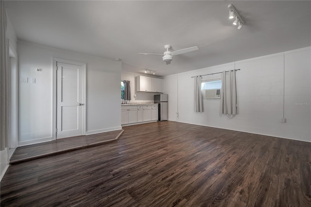 unfurnished living room with ceiling fan, track lighting, sink, and dark hardwood / wood-style floors