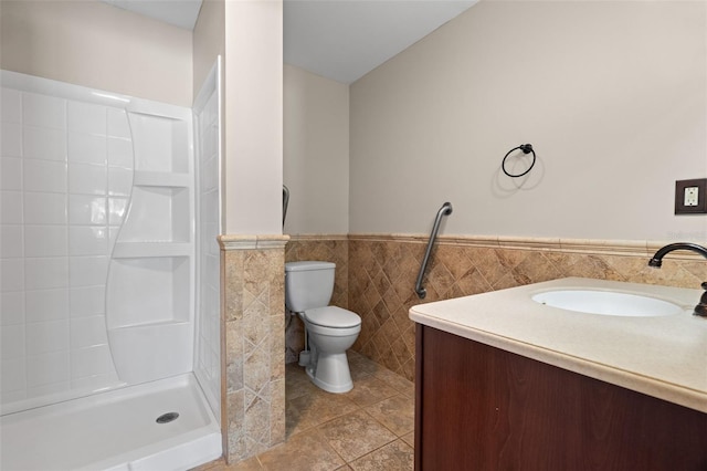 bathroom featuring tile patterned flooring, a shower, toilet, vanity, and tile walls