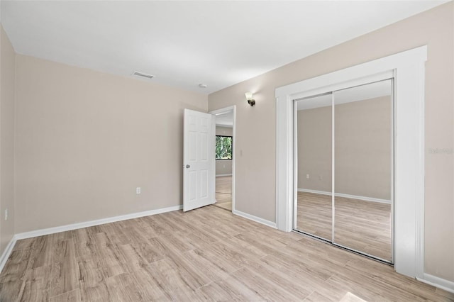 unfurnished bedroom featuring light hardwood / wood-style flooring and a closet