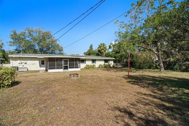 rear view of property featuring a sunroom and a yard