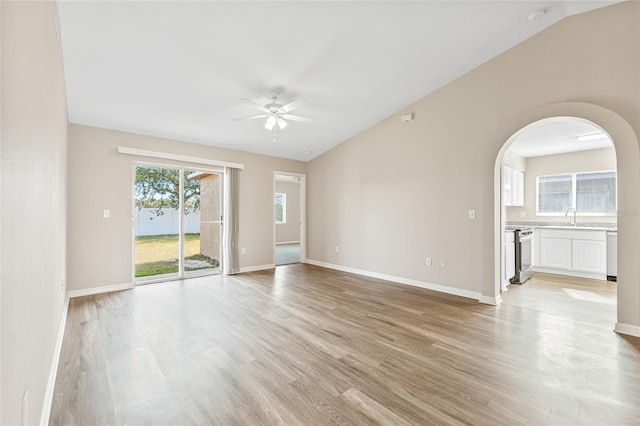 empty room with ceiling fan, light wood-type flooring, sink, and vaulted ceiling