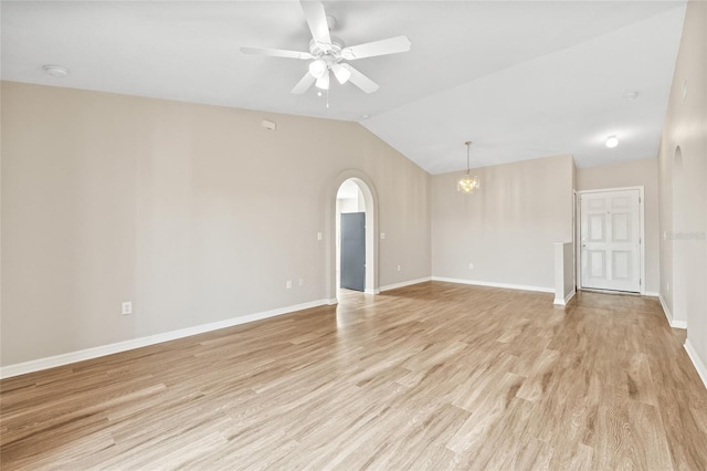 empty room with ceiling fan with notable chandelier, light hardwood / wood-style floors, and lofted ceiling