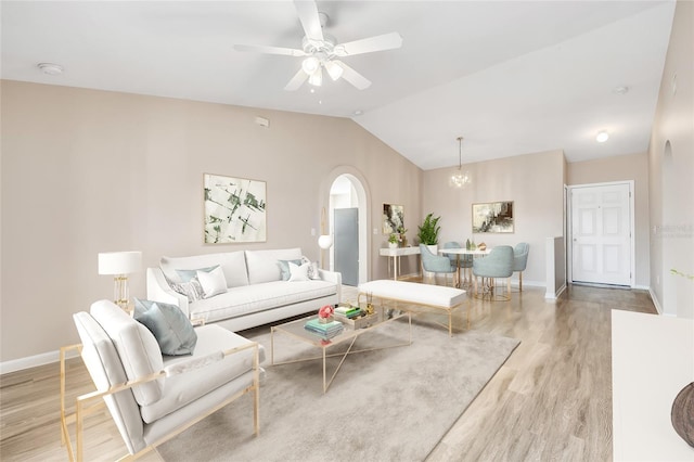 living room featuring ceiling fan with notable chandelier, light wood-type flooring, and lofted ceiling