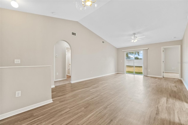 unfurnished living room featuring ceiling fan with notable chandelier, light hardwood / wood-style floors, and vaulted ceiling