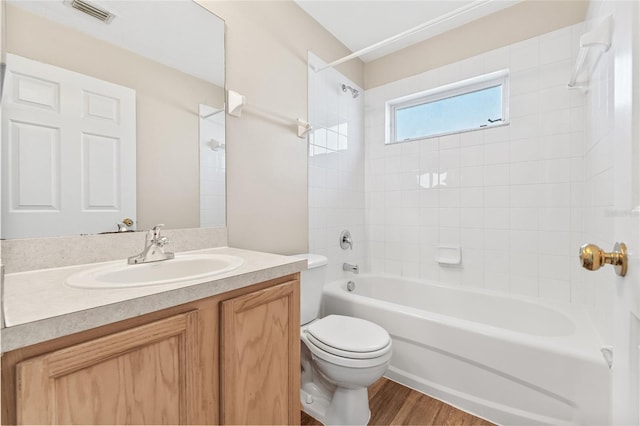 full bathroom featuring tiled shower / bath combo, toilet, wood-type flooring, and vanity