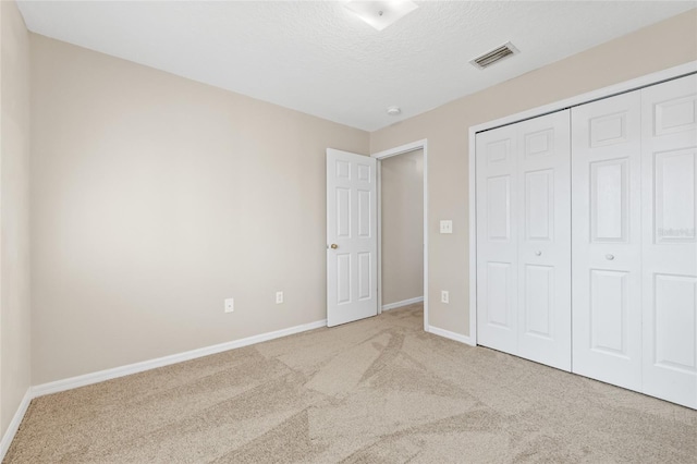 unfurnished bedroom featuring a closet, light colored carpet, and a textured ceiling