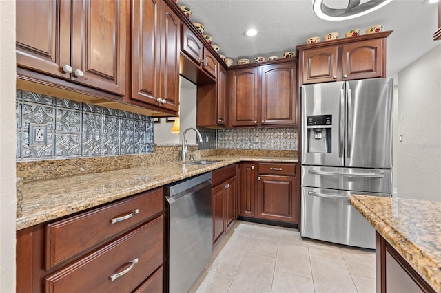 kitchen with light stone countertops, light tile patterned flooring, appliances with stainless steel finishes, sink, and backsplash