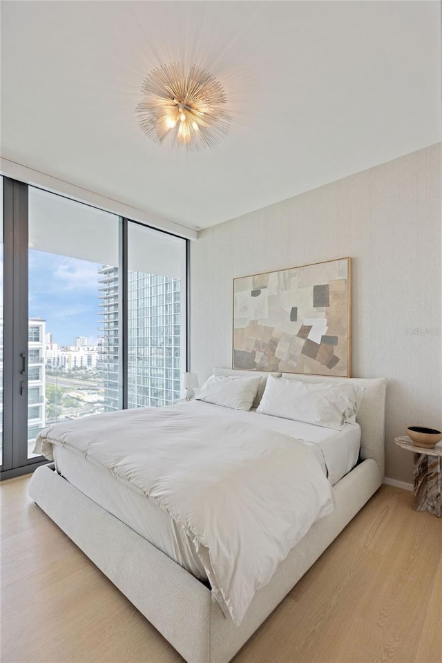 bedroom with access to outside, hardwood / wood-style floors, and a wall of windows