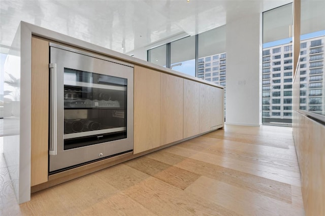 interior space with light wood-type flooring, a wall of windows, and beverage cooler