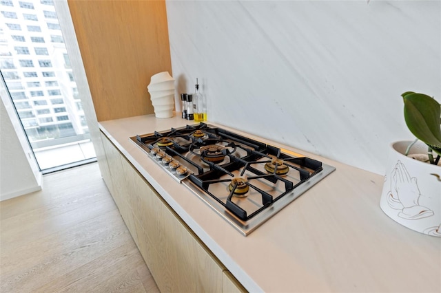 kitchen with light hardwood / wood-style floors, light brown cabinetry, and stainless steel gas stovetop