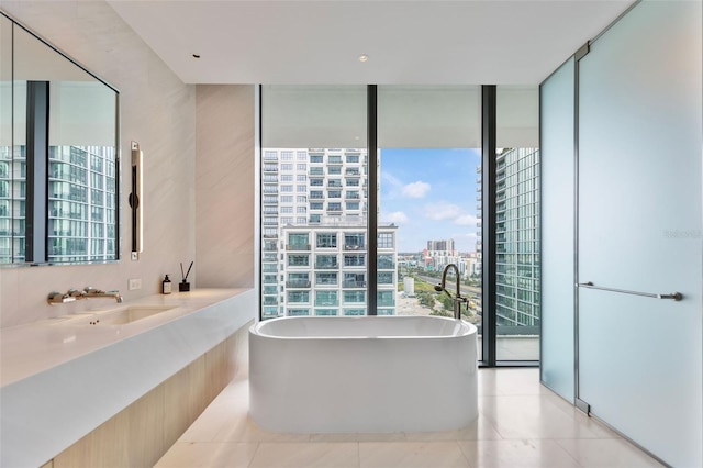 bathroom with vanity, tile patterned floors, a wall of windows, and a bathing tub