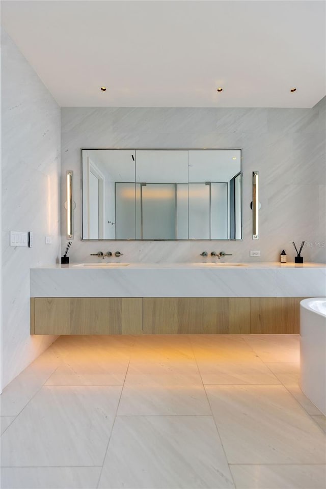 bathroom with vanity, a relaxing tiled tub, and tile walls