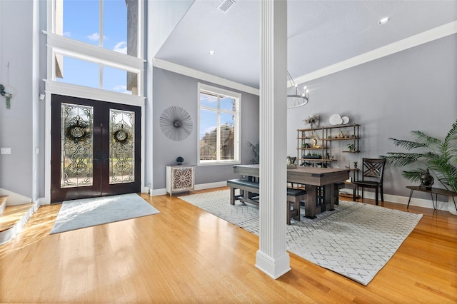 entrance foyer featuring ornamental molding, french doors, wood-type flooring, and decorative columns