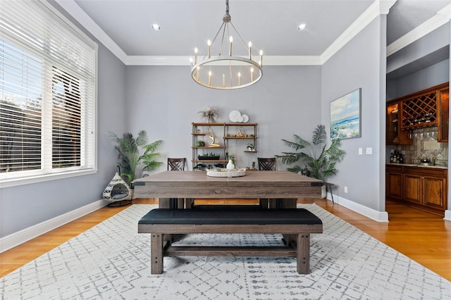 dining space featuring an inviting chandelier, light wood-type flooring, and crown molding