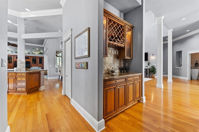 interior space with ornamental molding, tasteful backsplash, light hardwood / wood-style floors, and ornate columns