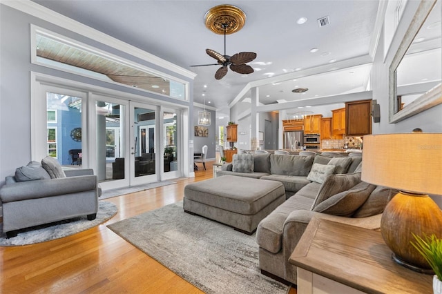 living room with light hardwood / wood-style flooring, vaulted ceiling, ornamental molding, and plenty of natural light