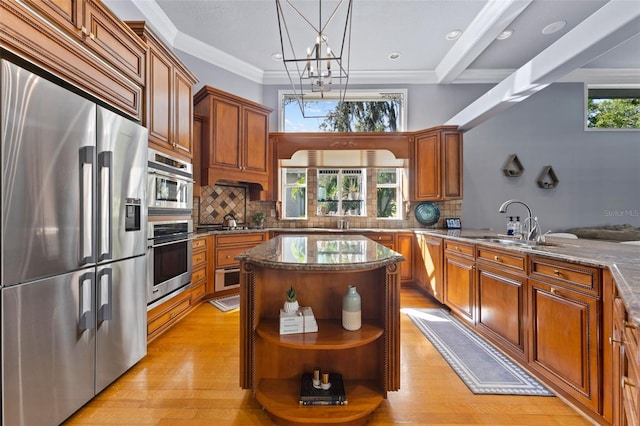 kitchen with stainless steel appliances, plenty of natural light, a notable chandelier, crown molding, and light wood-type flooring