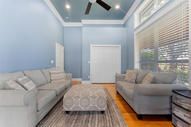 living room with ceiling fan, plenty of natural light, light hardwood / wood-style flooring, and ornamental molding