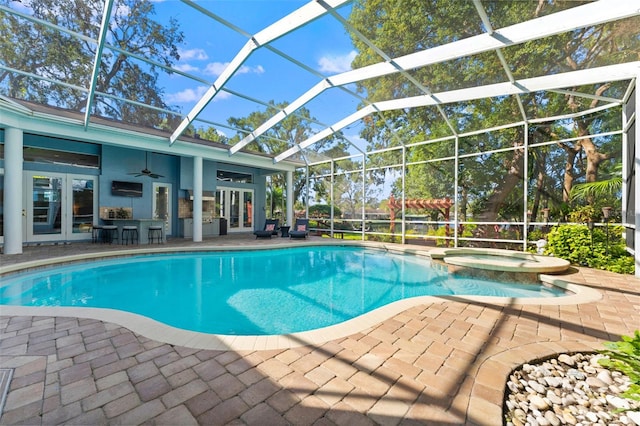 view of pool with glass enclosure, ceiling fan, an in ground hot tub, and a patio area