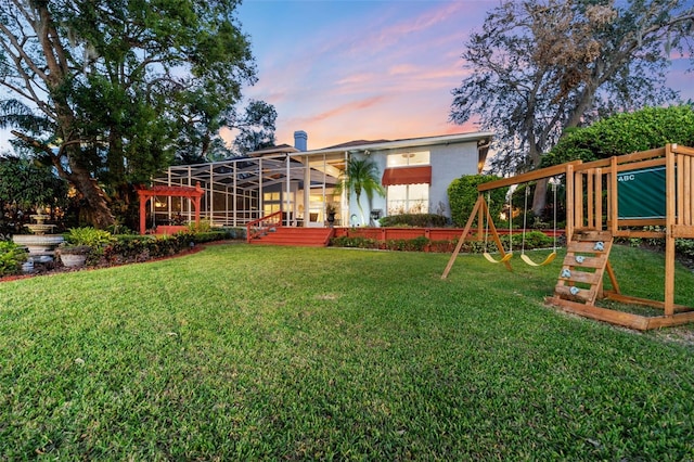 exterior space featuring a lawn, a playground, and glass enclosure