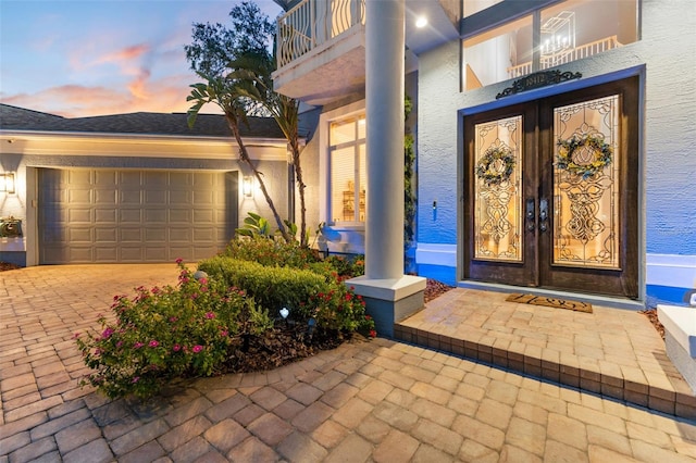 exterior entry at dusk featuring french doors and a garage