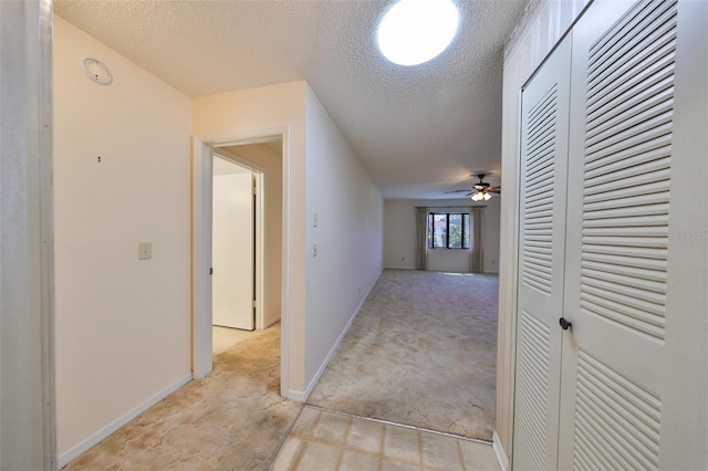 hallway with light carpet and a textured ceiling