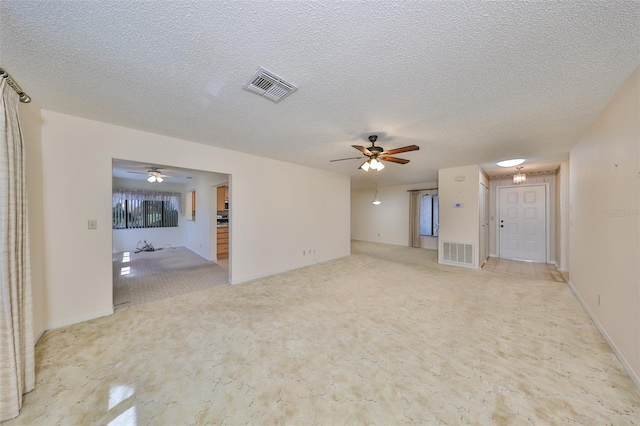 spare room featuring a textured ceiling, light colored carpet, and ceiling fan