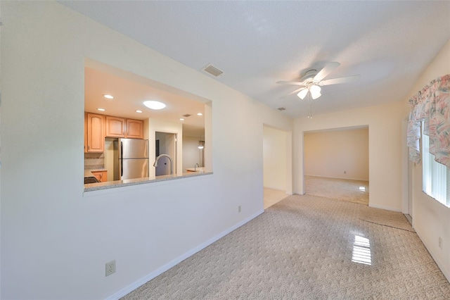 empty room featuring light colored carpet and ceiling fan