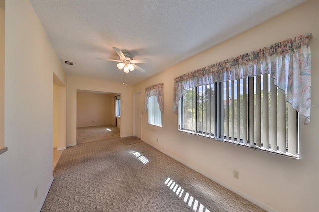 carpeted spare room with a textured ceiling and ceiling fan