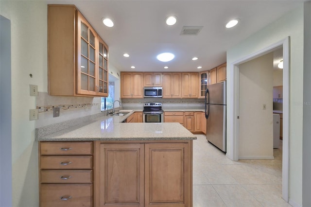 kitchen featuring kitchen peninsula, light tile patterned floors, appliances with stainless steel finishes, light stone countertops, and sink