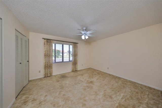 carpeted spare room featuring ceiling fan and a textured ceiling