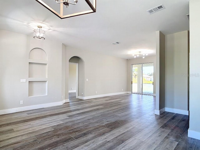 unfurnished living room with hardwood / wood-style flooring, a chandelier, and built in features