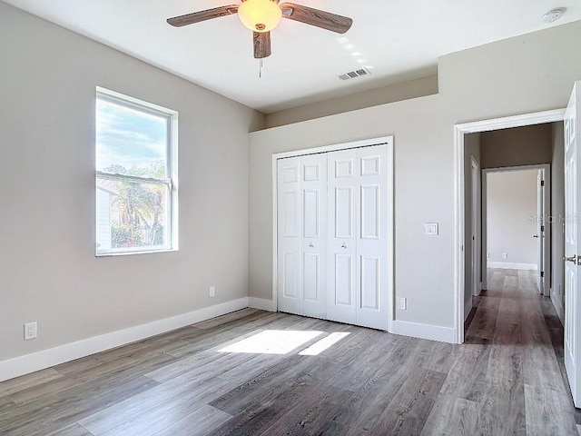 unfurnished bedroom with a closet, hardwood / wood-style flooring, and ceiling fan