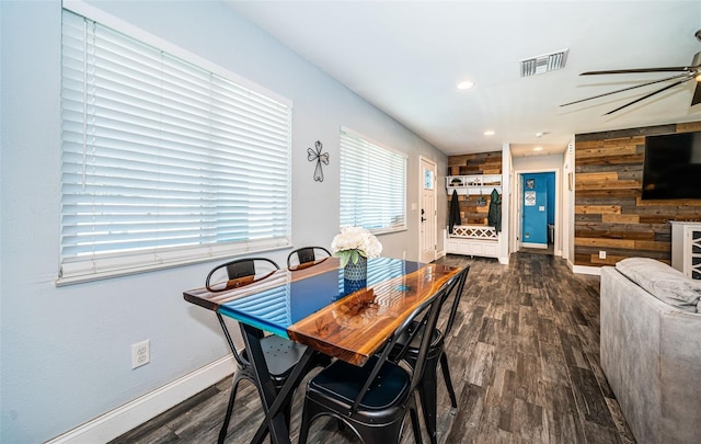 dining space with wood walls, dark hardwood / wood-style floors, and ceiling fan