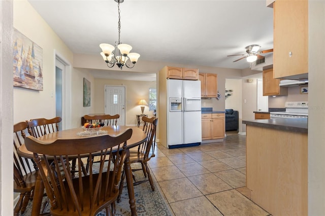 tiled dining area with ceiling fan with notable chandelier