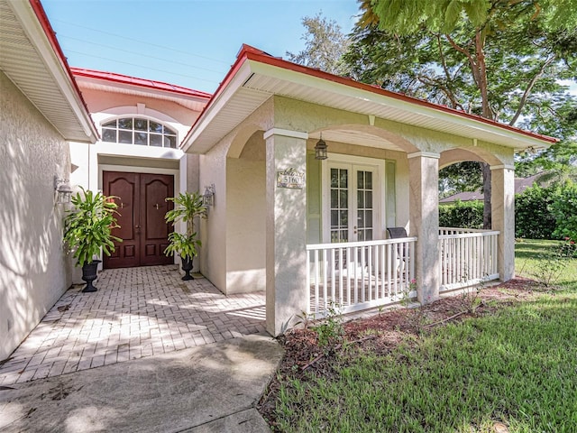 entrance to property with a porch and a yard