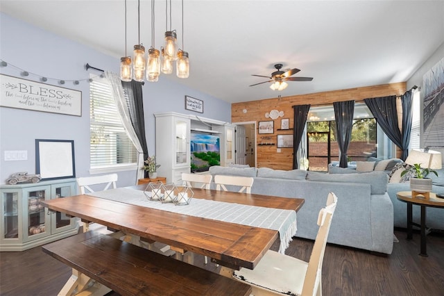 dining space featuring wooden walls, ceiling fan, and dark hardwood / wood-style flooring