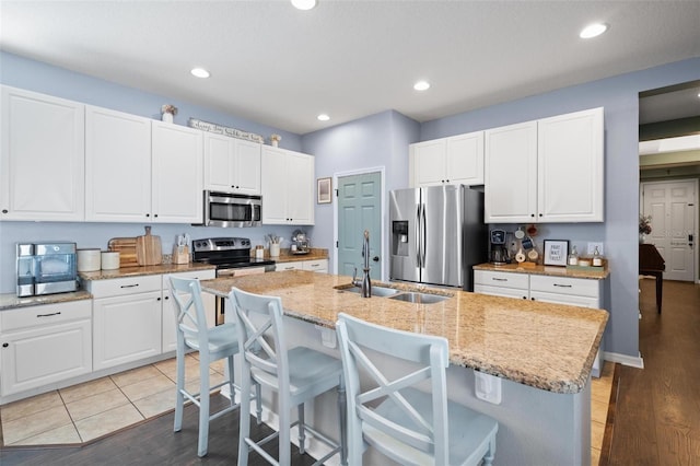 kitchen with stainless steel appliances, a center island with sink, and sink