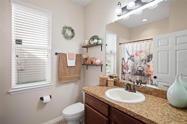 bathroom with vanity, toilet, and a healthy amount of sunlight