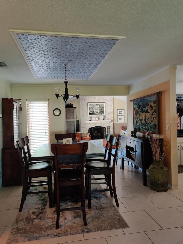 dining room featuring crown molding, light tile patterned floors, a chandelier, a fireplace, and a textured ceiling