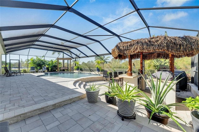 view of swimming pool featuring exterior bar, a grill, glass enclosure, and a patio area