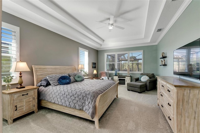 bedroom with a raised ceiling, light carpet, and ceiling fan